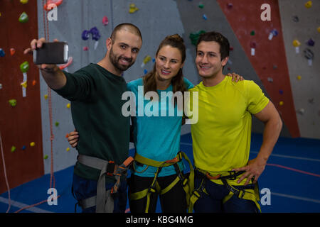 Trainer unter selfie mit Athleten durch Mobiltelefon in der Turnhalle Stockfoto