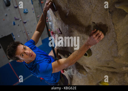 Hohen winkel Portrait von männlichen Athleten Kletterwand im Fitness Studio. Stockfoto