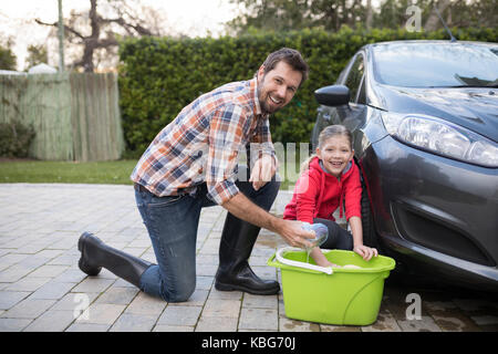 Portrait von Jugendmädchen und Vater ein Auto waschen an einem sonnigen Tag Stockfoto