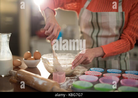 Den mittleren Abschnitt der Frau mischen Eier und Mehl in eine Schüssel geben. Stockfoto