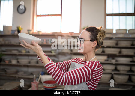 Weibliche Potter Überprüfung Schüssel in Keramikwerkstatt Stockfoto