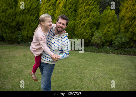 Junge Mädchen tanzen mit ihren Vätern Schultern im Park Stockfoto