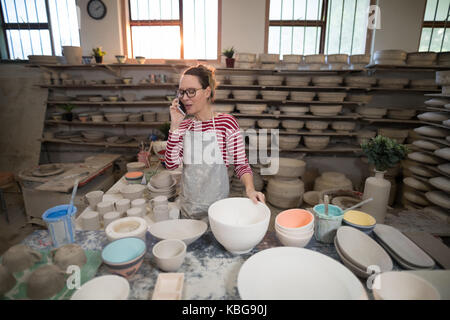 Weibliche potter Gespräch am Handy in der Töpferei Stockfoto