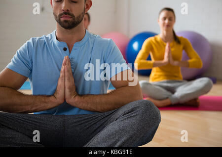 Yoga Lehrer mit Schüler meditieren im Gebet Position im Health Club Stockfoto