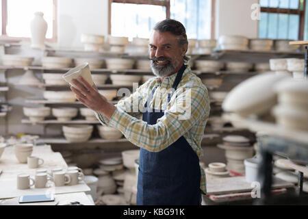 Männliche potter Kontrolle Becher in Töpferei Stockfoto