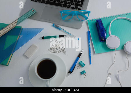 Overhead von Laptop, schwarzer Kaffee und Schreibwaren auf weißem Hintergrund Stockfoto