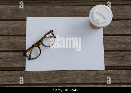 Overhead von Brillen, Einweg Glas und leeres Papier auf Holzbrett Stockfoto