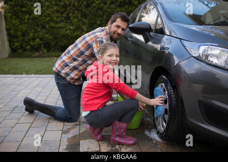 Portrait von Jugendmädchen und Vater ein Auto waschen an einem sonnigen Tag Stockfoto