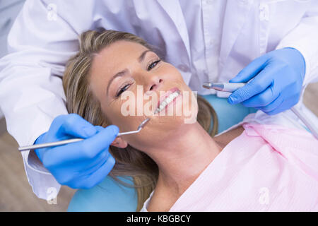 Hohen winkel Porträt der Frau durch Zahnarzt dolding Werkzeug an der Medizinischen Klinik Stockfoto