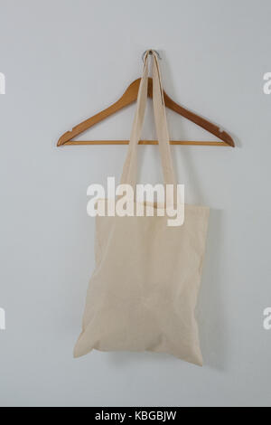 Beige Beutel auf Bügel gegen weiße Wand Stockfoto
