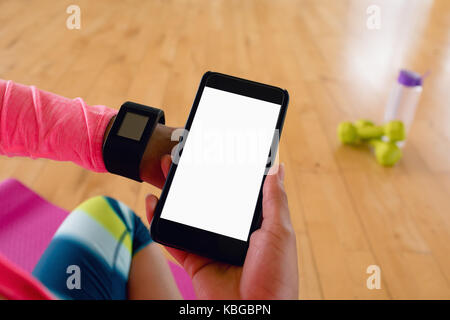 Frau mit mobilen abzuziehen, während sie erobert in der Turnhalle Stockfoto
