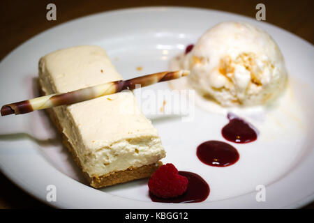 Eine weiße Schokolade Käsekuchen gepaart mit einer Bienenwabe Vanille Eis und ein rasberry Coulis Stockfoto