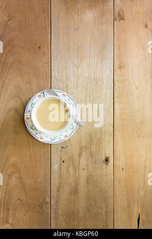 Kaffee und Milch Schale auf der Untertasse auf hölzernen Hintergrund, einen Löffel auf der Untertasse, flach Stockfoto