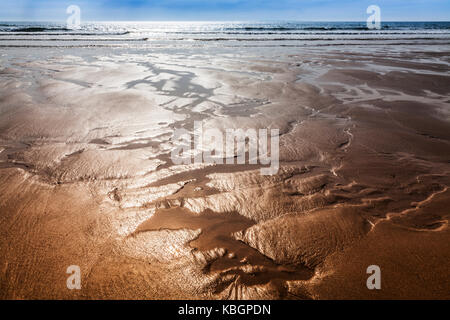 Die glitzernden Sand Bäche bilden abstrakte Muster am Strand. Stockfoto