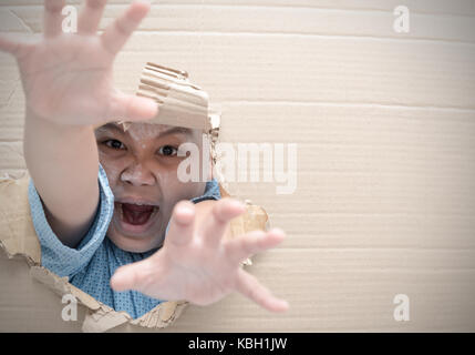 Zombie Kind Junge schreiend und erreichen die Hand durch das Loch auf Karton. Halloween tag Konzept. Kopieren Sie Platz. Stockfoto