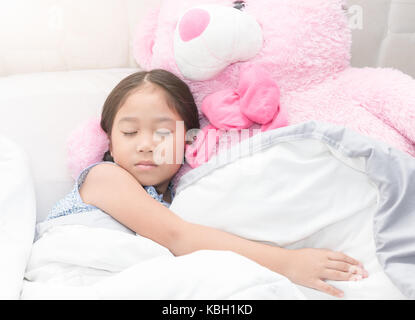 Süße asiatische Mädchen schlafen mit großen rosa Teddybär auf dem Bett, gesunde Konzept Stockfoto