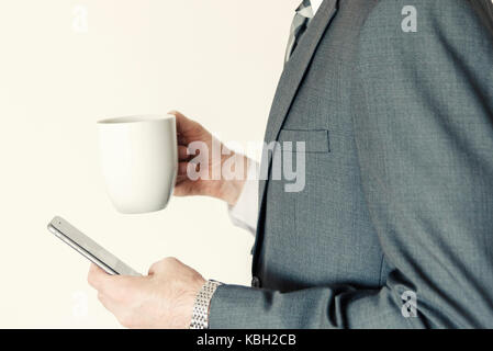 Headless professioneller Geschäftsmann Profil Seitenansicht mit Smart Handy, während Sie eine Tasse Kaffee im Büro horizontal. Stockfoto