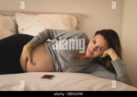 Porträt der schwangeren Frau auf dem Bett entspannen Stockfoto