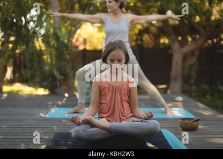 Enkelin und Oma Yoga im Garten an einem sonnigen Tag Stockfoto