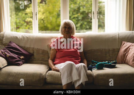 Ältere Frau auf Sofa im Wohnzimmer zu Hause sitzen Stockfoto