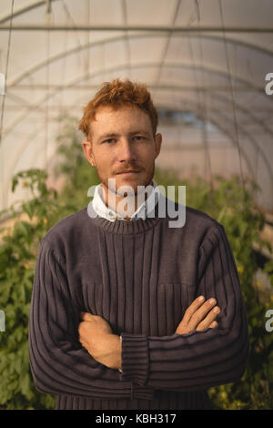 Portrait von Bauern Stehen mit gekreuzten Armen im Gewächshaus Stockfoto