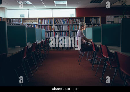 Mann an Schreibtisch in der Bibliothek Stockfoto