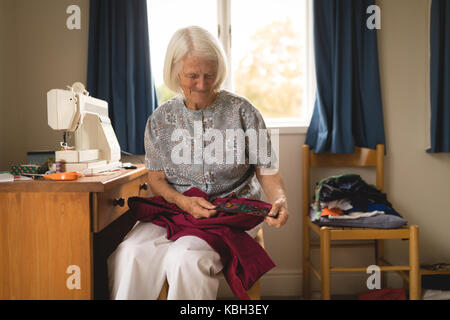 Ältere Frau an Pullover in Home Suchen Stockfoto