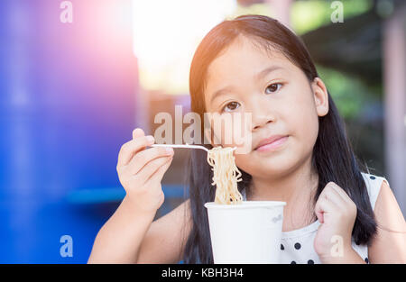 Cute asian kid Mädchen essen instand Nudel Schale, Fast food Konzept Stockfoto