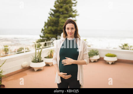 Portrait der schwangeren Frau, die auf der Terrasse Stockfoto