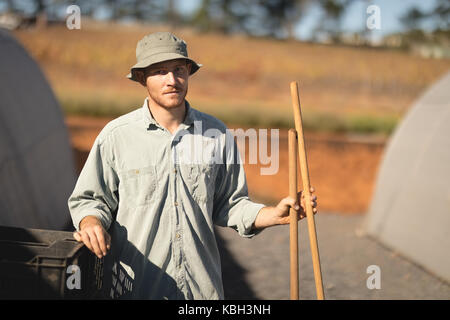 Portrait von Bauern stehen mit Werkzeugen in der Nähe von Treibhausgasen Stockfoto