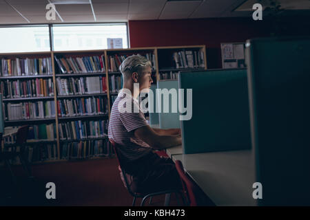 Mann an Schreibtisch in der Bibliothek Stockfoto