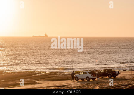 WALVIS BAY, NAMIBIA - Juli 2, 2017: Angler bei Sonnenuntergang am Strand in der Nähe von Long Beach in der Namib Wüste auf der atlantischen Küste von Namibia Stockfoto