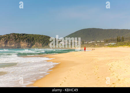 Dame in Rot laufen Joggen entlang Boomerang Beach in New South Wales, Australien Stockfoto