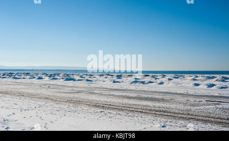 Gefrorenes Eis und Sanddünen am Strand im Winter in See unter strahlend blauem Himmel, in der Nähe der Georgian Bay, Ontario, Kanada. Stockfoto