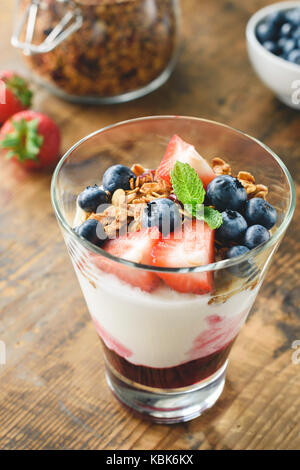 Joghurt mit Müsli, Blaubeeren und strawberies in Glas auf Holztisch. gesunder Snack, gesundes Frühstück Stockfoto