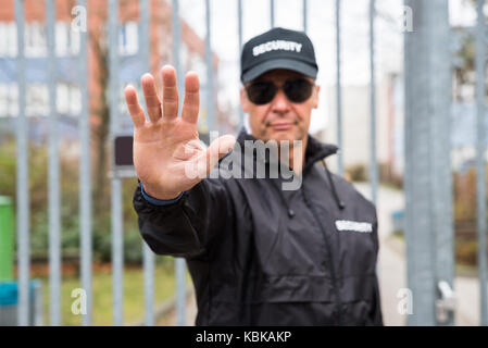 Zuversichtlich Security Guard, stop Geste gegenüber Gate Stockfoto
