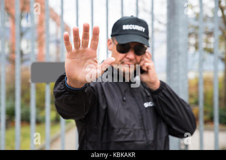 Zuversichtlich Security Guard, stop Geste gegenüber Gate Stockfoto