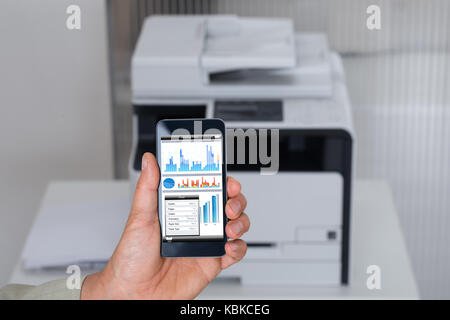 Zugeschnittenes Bild des Befehls Geschäftsmann, drucken Sie auf Smart Phone im Büro Stockfoto