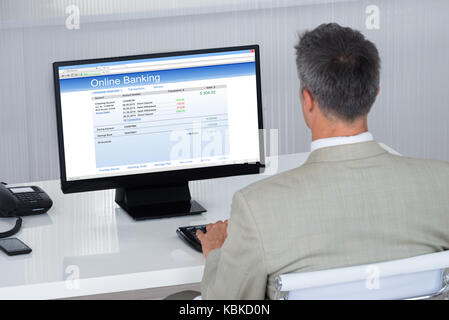 Ansicht der Rückseite des Geschäftsmann tun Online Transaktion am Schreibtisch im Büro Stockfoto