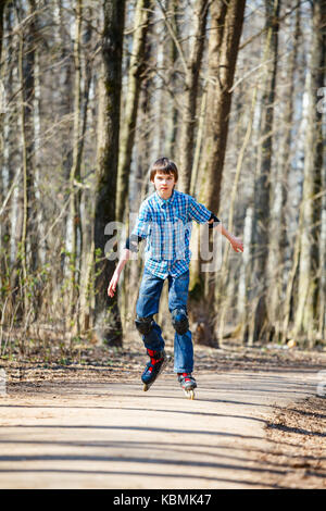 Kid Schlittschuhlaufen auf Inline-skates in Spring Park Stockfoto