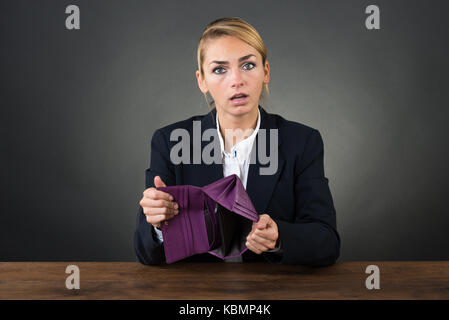 Porträt der jungen Geschäftsfrau, leer Kupplung am Schreibtisch über grauer Hintergrund Stockfoto