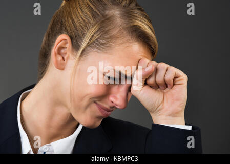 Deprimiert junge geschäftsfrau schlagende Hand auf den Kopf über grauer Hintergrund Stockfoto