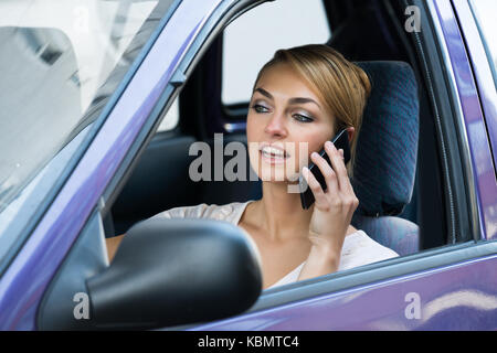 Junge Frau mit Handy während der Fahrt Auto Stockfoto