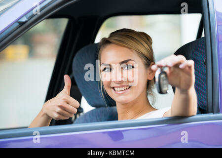 Porträt der glückliche junge Frau, die Gestik, die Daumen hoch halten Sie Taste im Auto. Stockfoto