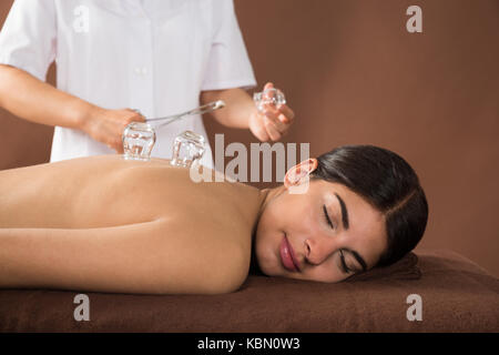 Junge Frauen, die auf der Vorderseite mit Schröpfen Behandlung auf der Rückseite Stockfoto