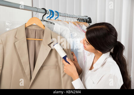 Weibliche Reiniger in Wäsche Shop Entfernen von Fusseln von Kleidung mit Kleber Walze Stockfoto