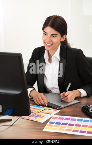 Weibliche Designer über Grafik Tablett mit Farbmuster am Schreibtisch Stockfoto