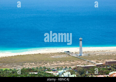 Blick von einem Hügel in den wunderschönen, endlosen Strand von Jandia in der Nähe von Morro Jable mit dem Leuchtturm von Jandia, Fuerteventura. Stockfoto