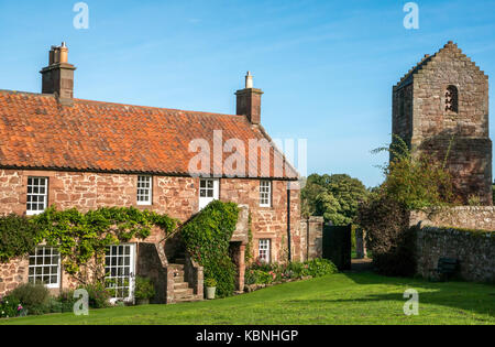 Sonnigen Tag in Stenton Village Green, East Lothian, Schottland, Großbritannien mit roten Schutt Stone Cottages und Tower dovecot mit blauem Himmel Stockfoto