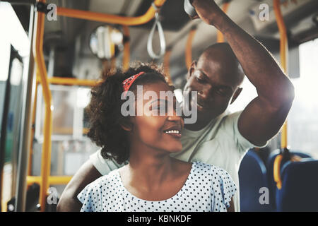 Liebevolle junge afrikanische Paar lächelnd an einander beim Reiten zusammen in einem Bus Stockfoto